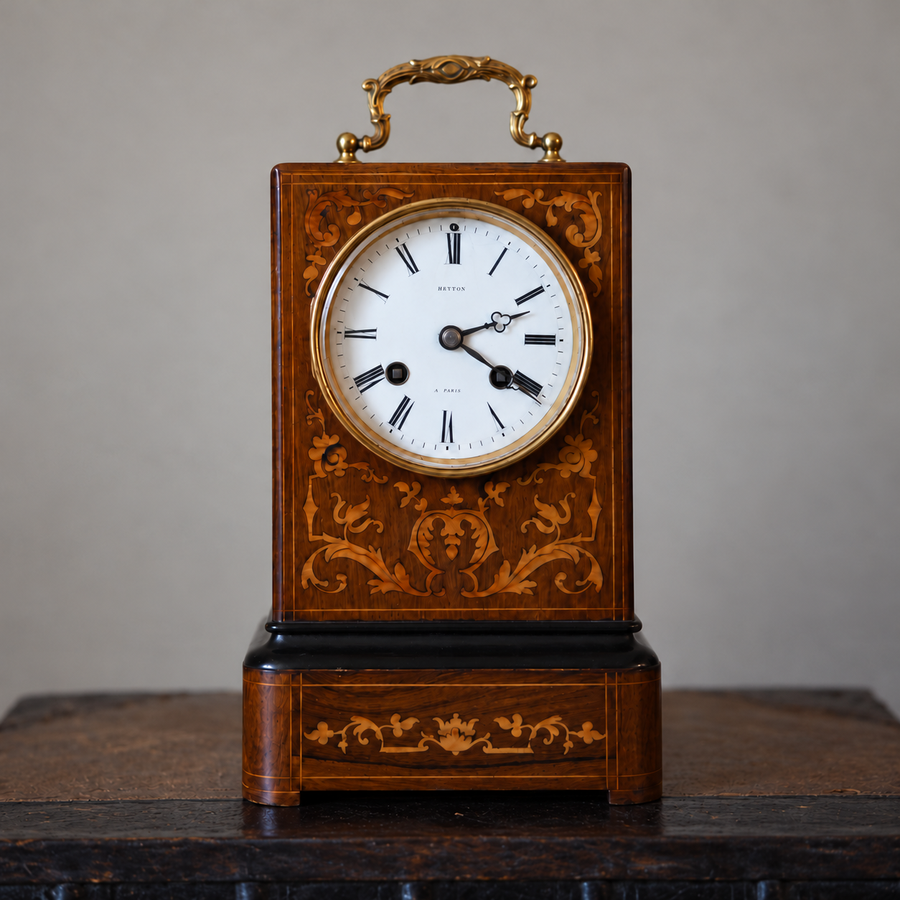 Front view of the antique French Hatton mantel clock, with floral marquetry, Roman numeral dial and raised brass handle.