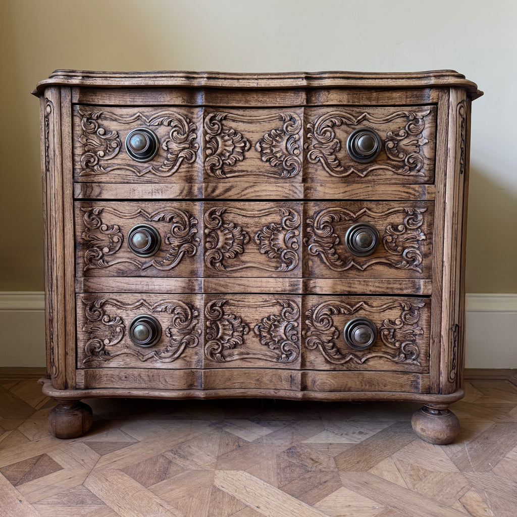 Wooden dresser with intricate carvings and round knobs.